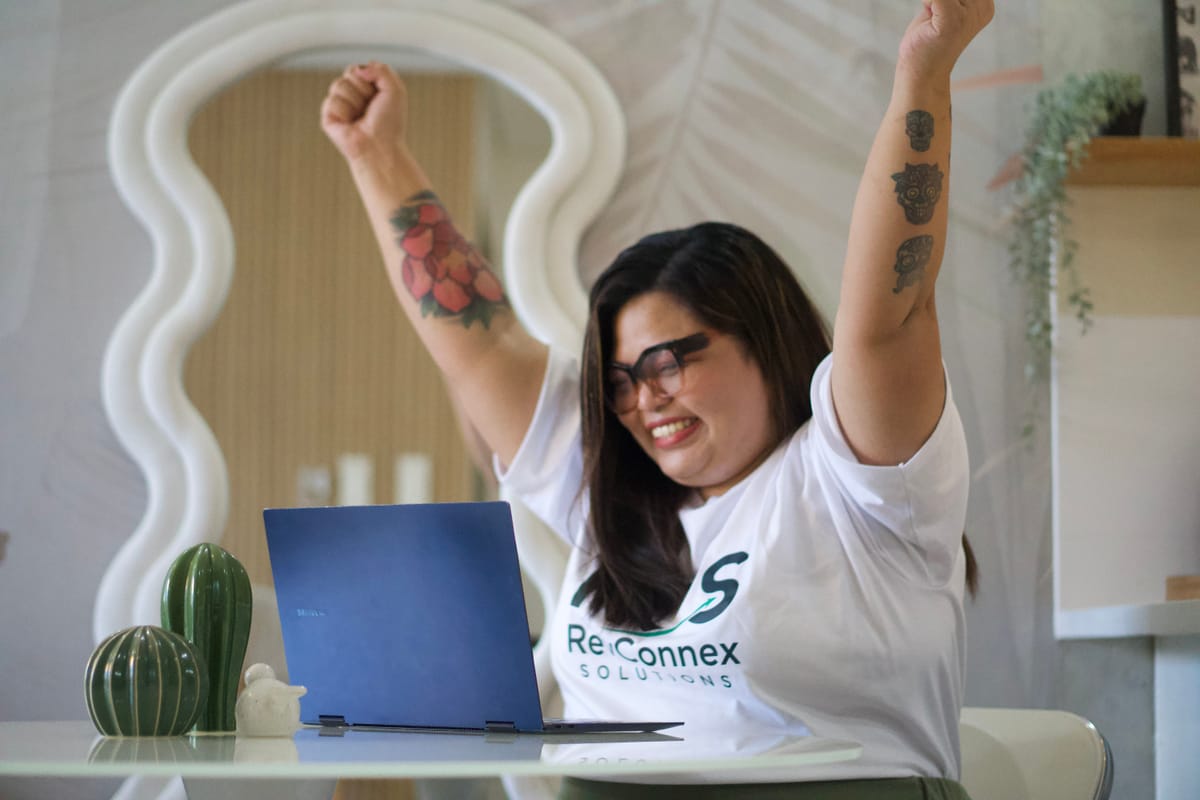 A RevConnex VA celebrating a win at her laptop, working from home
